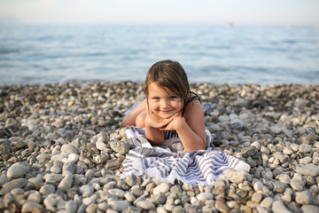 joyful girl child on a towel by the sea