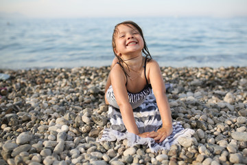joyful girl child on a towel by the sea