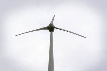 Windmill turbine close-up photo on cloudy background.