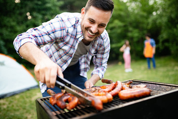 Man cooking meat on barbecue grill at outdoor summer party - obrazy, fototapety, plakaty