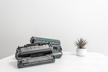 Cartridges group lie on an office white table against a white wall.