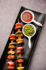 Barbecue or tandoori Mushroom Tikka, served in a plate with green chutney and ketchup. selective focus