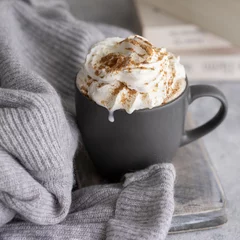 Fototapeten Mug of hot chocolate with mil cream and cinnamon wrapped in wool grey sweater. Winter relax mood and hygge concept. Close up © vasanty