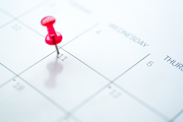 Red push pin on calendar 11th day of the month