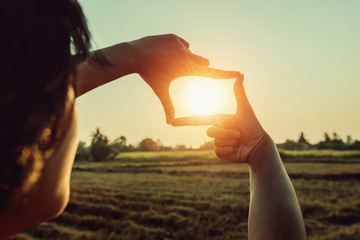 woman hand framing view distant over sunset. business concept - obrazy, fototapety, plakaty
