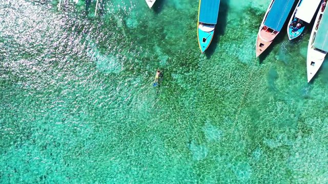 Tourists Enjoy Swimming On The Beach With Fishing Boats Floating By The Sea - Beautiful Tourist Destination - Aerial Shot in Philippines -