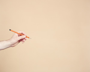 Eine Hand hält einen orangefarbenen Bleistift