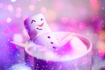 Cute little snowman made from marshmallows bathing in a mug with hot chocolate 