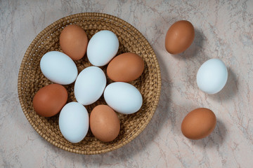 several fresh chicken eggs in a straw basket on a wooden background. Healthy eating concept.