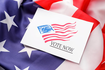 Fototapeta na wymiar Paper with text VOTE NOW on USA flag