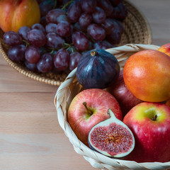 fresh fruits and red grape berries in a straw basket on a wooden background