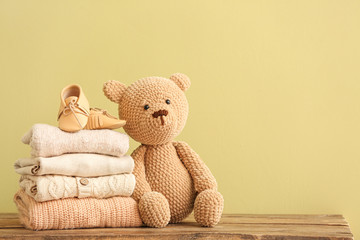 Stack of baby clothes and toy on table - obrazy, fototapety, plakaty