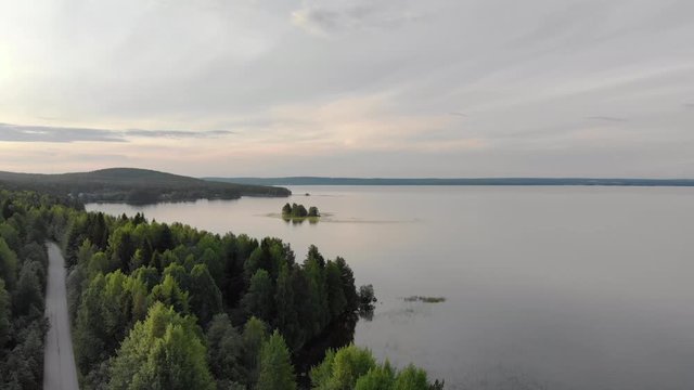 The magnificent landscape of the Northern nature. Coastal zone of lake Onega near dense coniferous forest with a country road in Karelia. Aerial view