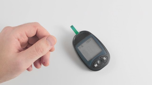 Measuring blood glucose sugar with a personal glucometer. The medical device shows the norm. The hand in the frame shows the thumb up. Concept prevention of diabetes.