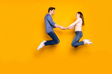 Fototapeta na wymiar Full body profile side photo of funky two students married people jump relax rest hold hand feel rejoice emotions wear blue pink outfit sneakers isolated over yellow color background