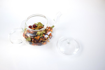 Fruit tea (tea leaves) in a glass teapot on a white background. Breakfast and tea party concept.