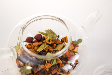 Fruit tea (tea leaves) in a glass teapot on a white background. Breakfast and tea party concept.