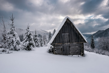 wooden abandoned cabin in winter mountains