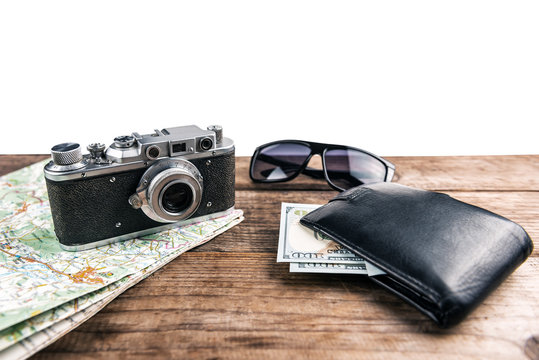 wallet, vintage camera, map and money on wooden background
