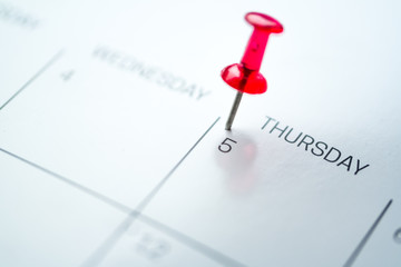 Red push pin on calendar 5th day of the month