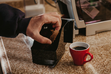 Fototapeta na wymiar Hand holds tablet of compressed coffee. Near cup of coffee