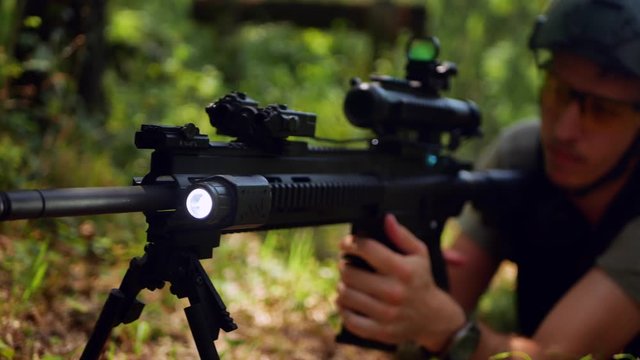 A sport shooters prepares his automatic machine gun and takes aim.  4k