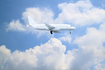 Fototapeta na wymiar white passenger plane comes in to land with natural background of white clouds and blue sky
