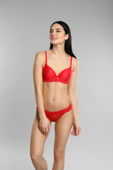 Fototapeta premium Beautiful young woman in red underwear on grey background