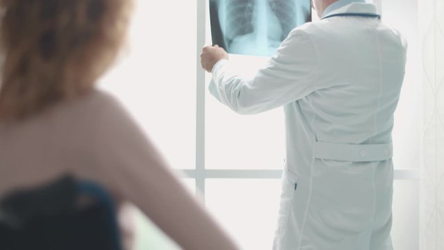 Doctor checking a radiography of a patient in wheelchair