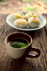 Brown hot coffee mug made of ceramic Put it on an old wooden table and dessert in the background, along with a light morning.