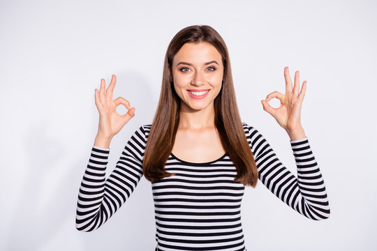 Portrait of charming lady showing ok sign looking with beaming smile wearing striped sweater isolated over white background
