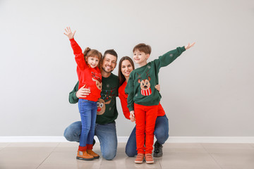 Obraz premium Happy family in Christmas clothes near light wall