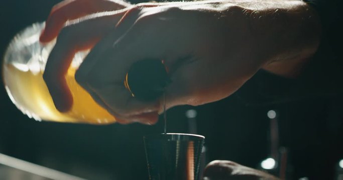 Close up of a professional bartender is serving an alcoholic cocktail with ice cubes to customers at the bar or disco club.