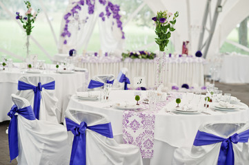 Beautiful wedding set decoration in the restaurant. Chairs with violet ribbons.
