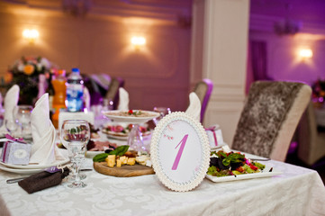 Beautiful wedding set decoration in the restaurant. Number 1 on table.