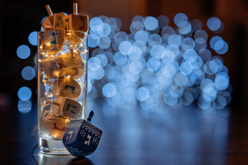 jewish holiday Chanukah/Hanukkah with wooden dreidels / sovivon (spinning top) in the glass over glitter shiny background. Traditional invitation card design - obrazy, fototapety, plakaty