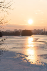 sunset over a river covered in ice and snow