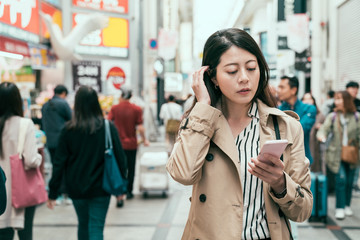 Lifestyle concept. Close up of young charming asian woman in coat smiling chatting with boyfriend on smartphone. office lady shopping and walking in shinsaibashi and using cellphone talking online.