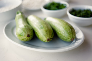 Baby zucchini on a white plate background. over white wooden table.  Organic food.