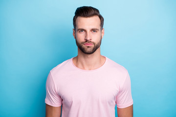 Close up photo of amazing macho guy standing not smiling looking seriously on camera wear casual pink t-shirt isolated over bright blue color background