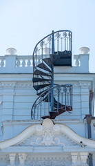 spiral metal staircase on the wall of the house leading to the roof