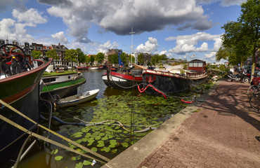 Amsterdam, Holland, August 2019. View of the Amstel River, outskirts of the city. A large moored boat is used as a houseboat. Sunny day with blue sky and white clouds.