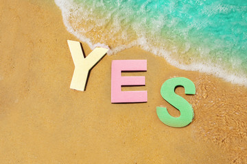 Yes sign floating in water near beach sand edge