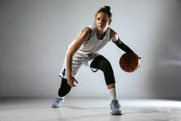  Young caucasian female basketball player of team in action, motion in run isolated on white wall background. Concept of sport, movement, energy and dynamic, healthy lifestyle. Training, practicing. © master1305