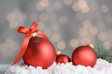 Fototapeta na wymiar Beautiful Christmas balls with snow on table against blurred lights