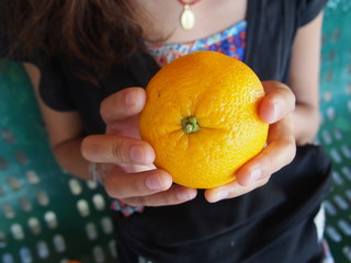 Young woman holds in her hand mandarin orange at the town of Castrojeriz, Camino de Santiago, Way of St. James, Journey from Hornillos del Camino to Castrojeriz, French way, Spain