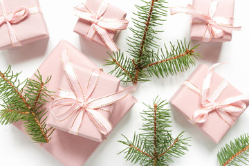 Christmas flat lay. Holiday gifts in boxes in pink packaging and fir branches on a white background with copy space, top view..