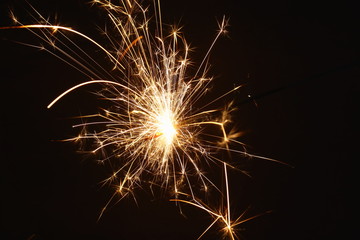 Christmas and New Year's illumination. Burning sparklers scatter bright exploding strips of sparks on a dark background.