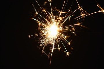 Fototapeta premium Christmas and New Year's illumination. Burning sparklers scatter bright exploding strips of sparks on a dark background.