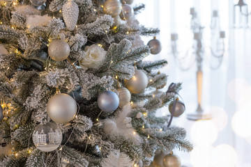 Christmas tree decorated in retro style with white, silver and blue balls, feathrs, christmas cones. Place for text